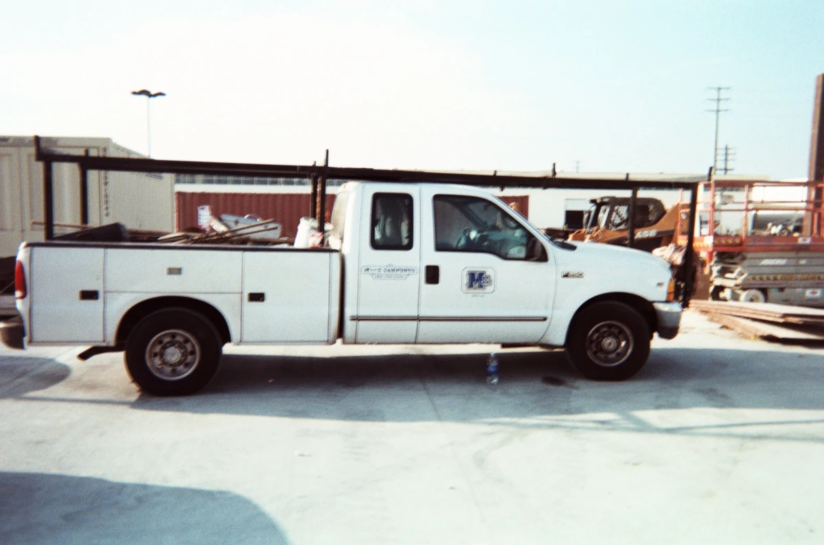 An archival photograph of an M Bar C work truck at a steel construction site